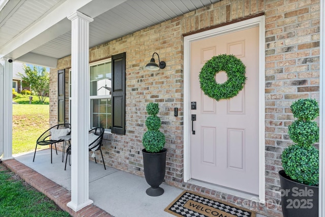 property entrance featuring covered porch and brick siding