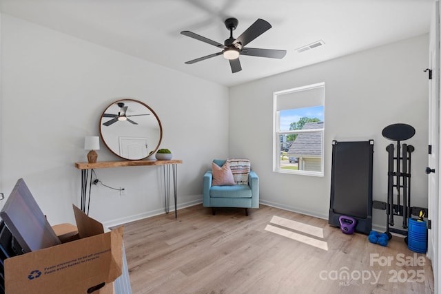 living area featuring baseboards, ceiling fan, wood finished floors, and visible vents