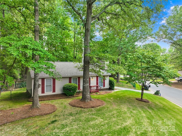 ranch-style house featuring a shingled roof, fence, and a front yard
