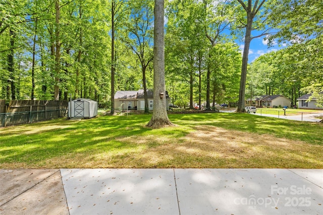 view of yard featuring an outdoor structure, fence, and a shed