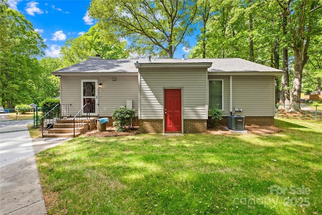 view of front facade featuring fence, central AC unit, and a front lawn