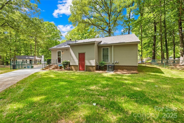 view of front of home featuring central air condition unit, fence, driveway, and a front yard
