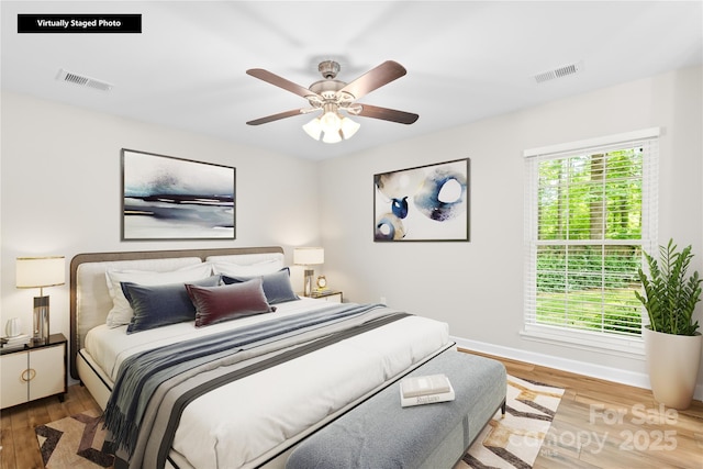 bedroom featuring a ceiling fan, baseboards, visible vents, and wood finished floors