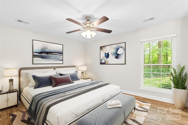 bedroom featuring ceiling fan, baseboards, visible vents, and wood finished floors