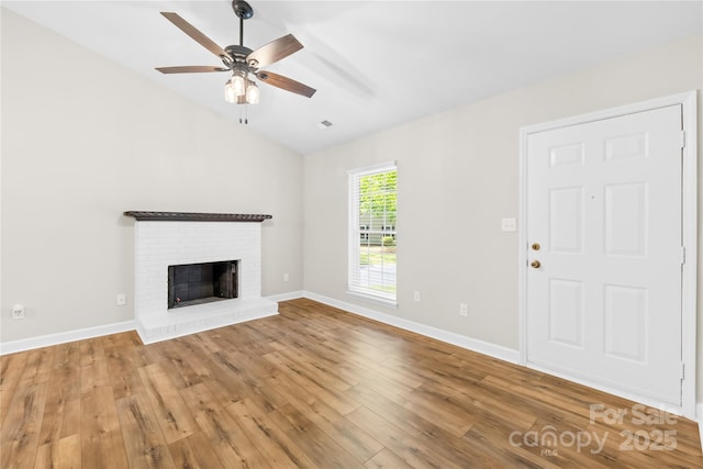 unfurnished living room with light wood finished floors, ceiling fan, vaulted ceiling, and a fireplace
