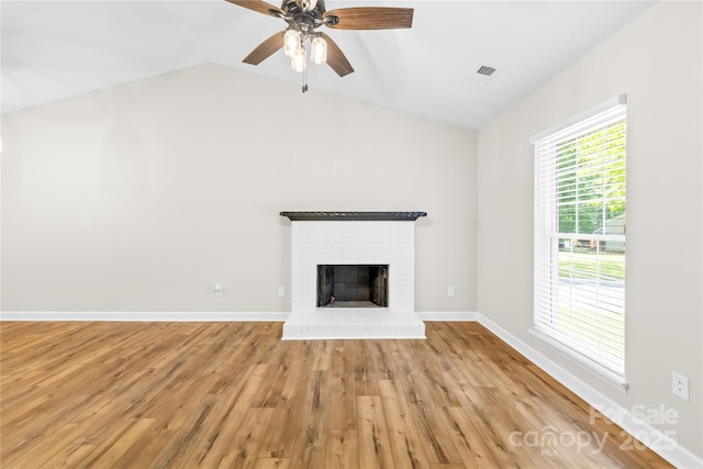 unfurnished living room featuring ceiling fan, a brick fireplace, light wood-style flooring, vaulted ceiling, and visible vents