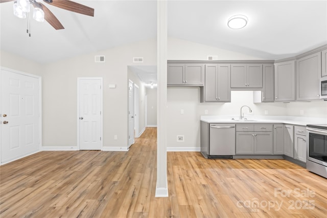 kitchen with gray cabinets, ceiling fan, appliances with stainless steel finishes, a sink, and lofted ceiling