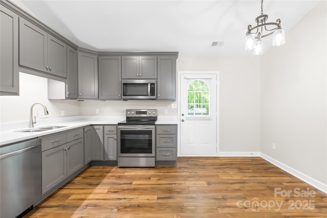 kitchen featuring a sink, a chandelier, gray cabinets, stainless steel appliances, and visible vents