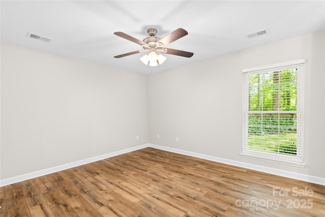 empty room with baseboards, visible vents, and wood finished floors