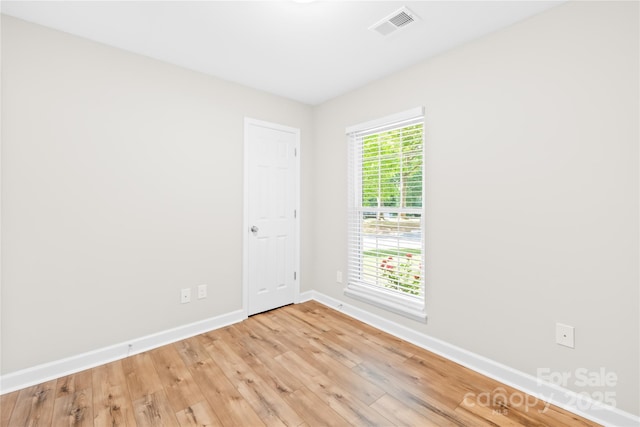 spare room featuring baseboards, light wood-style floors, and visible vents