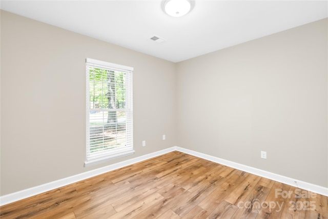 empty room with baseboards, light wood finished floors, and visible vents