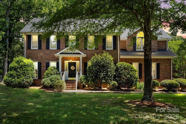 view of front facade with brick siding and a front yard