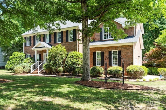 view of front facade with brick siding and a front lawn