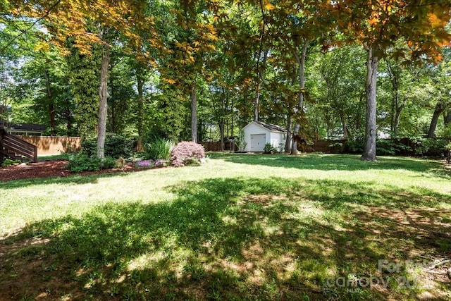 view of yard with an outbuilding, fence, and a shed