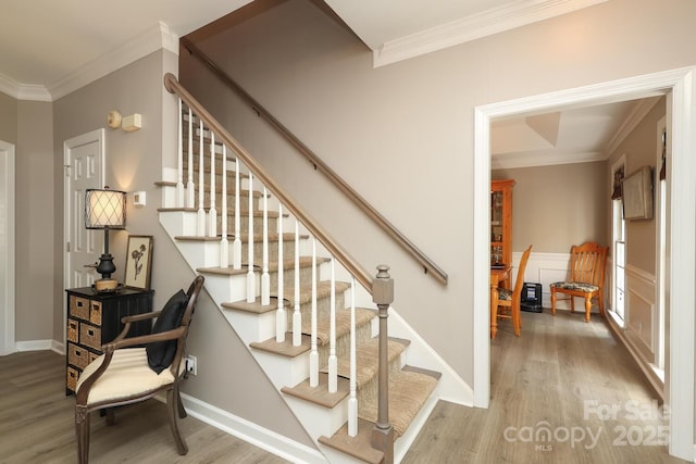 staircase with baseboards, ornamental molding, and wood finished floors