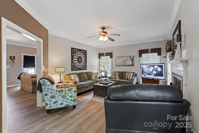 living room with light wood finished floors, plenty of natural light, a ceiling fan, and ornamental molding