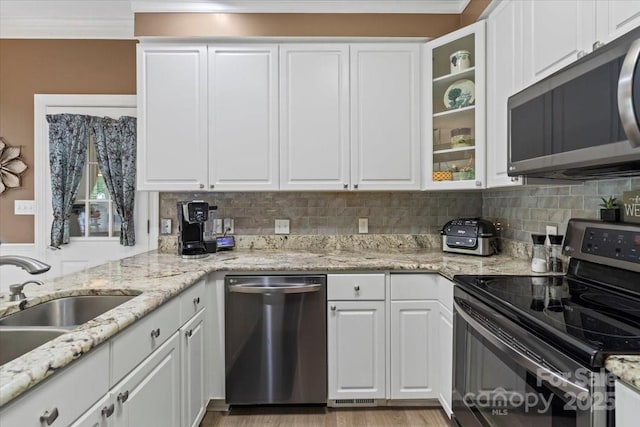 kitchen featuring appliances with stainless steel finishes, decorative backsplash, a sink, and white cabinetry