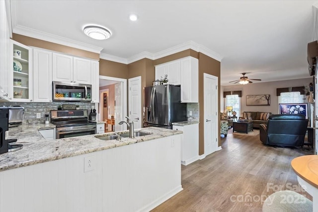 kitchen with a sink, white cabinetry, light stone countertops, backsplash, and appliances with stainless steel finishes