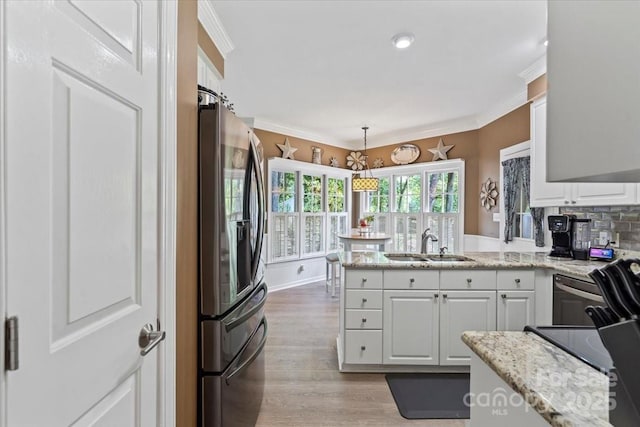 kitchen featuring a sink, a peninsula, stainless steel refrigerator with ice dispenser, white cabinets, and light wood-style floors