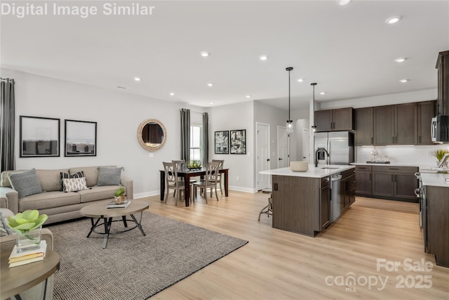 kitchen with light countertops, open floor plan, dark brown cabinets, and stainless steel appliances