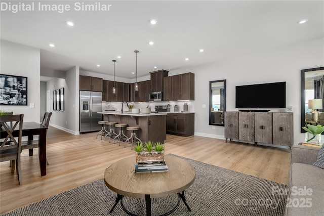 living room with light wood-style floors, recessed lighting, and baseboards