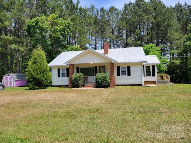 ranch-style home with a front lawn, a porch, a shed, a chimney, and metal roof