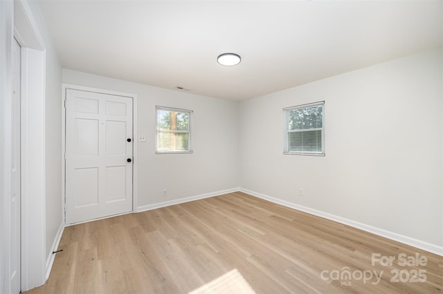 empty room featuring baseboards, light wood-type flooring, and visible vents