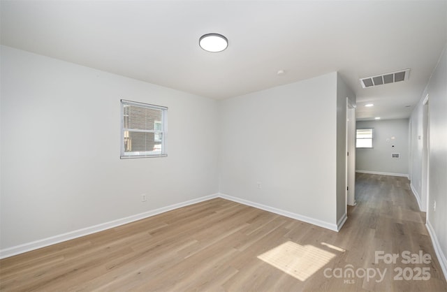 unfurnished room featuring baseboards, visible vents, and light wood-type flooring