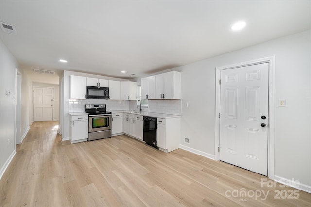 kitchen with a sink, light countertops, baseboards, visible vents, and black appliances