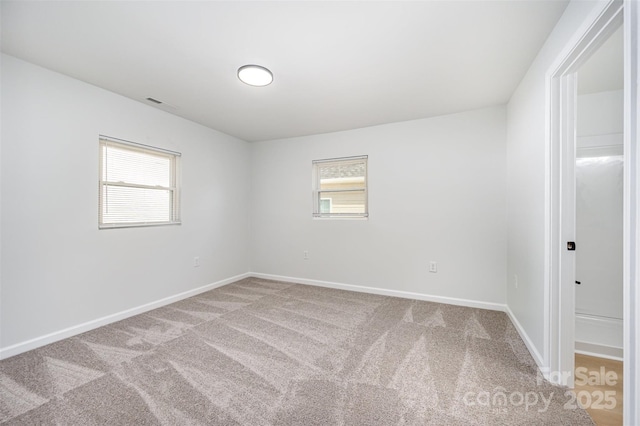 empty room with carpet floors, baseboards, and visible vents
