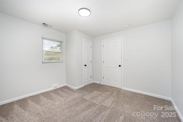 carpeted spare room featuring baseboards and visible vents