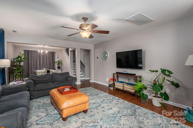 living room with visible vents, baseboards, ceiling fan with notable chandelier, and stairs