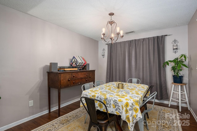 dining space featuring visible vents, baseboards, wood finished floors, and a chandelier