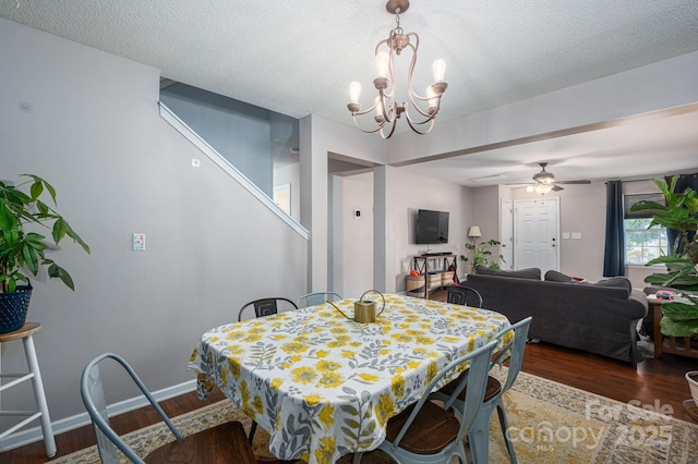 dining space with baseboards, ceiling fan with notable chandelier, wood finished floors, and stairway