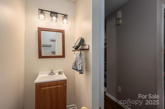 bathroom featuring vanity, baseboards, and wood finished floors