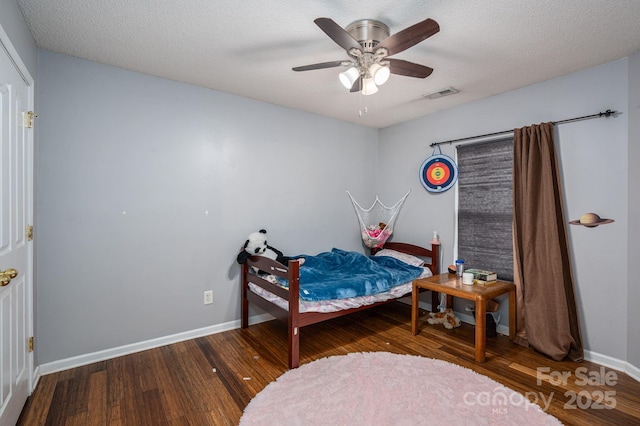 bedroom featuring a ceiling fan, baseboards, visible vents, and wood finished floors