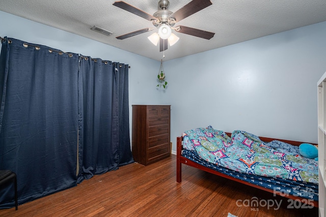 bedroom with visible vents, a ceiling fan, a textured ceiling, and wood finished floors