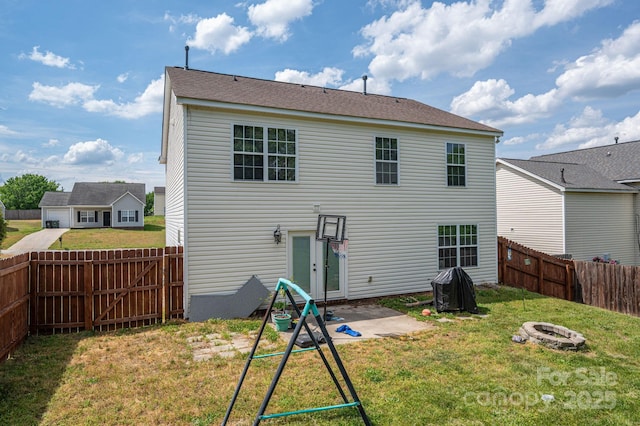 back of house with a fenced backyard, a patio, a yard, and a fire pit