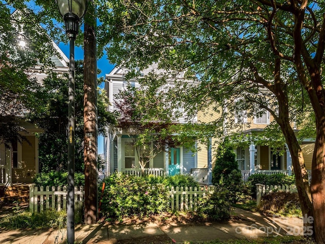 obstructed view of property with a porch and a fenced front yard