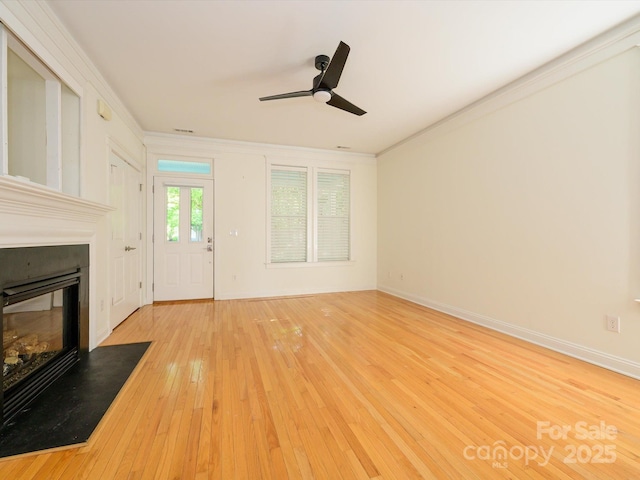 unfurnished living room with ceiling fan, ornamental molding, wood-type flooring, and a fireplace with flush hearth