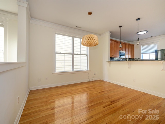 interior space with fridge, light wood-style floors, brown cabinets, and a kitchen bar