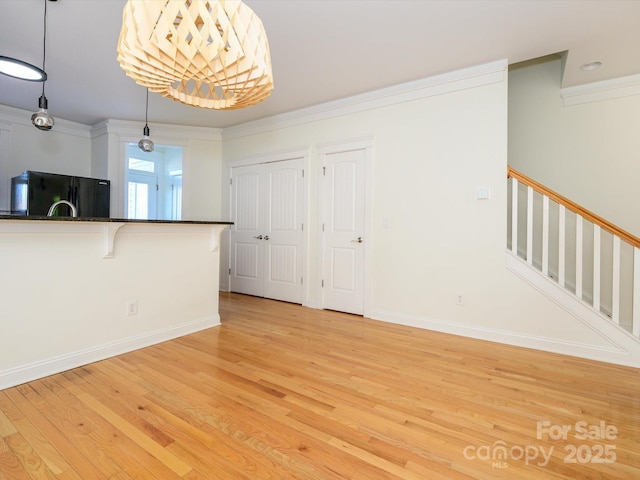 interior space featuring crown molding, light wood-style flooring, stairs, and baseboards