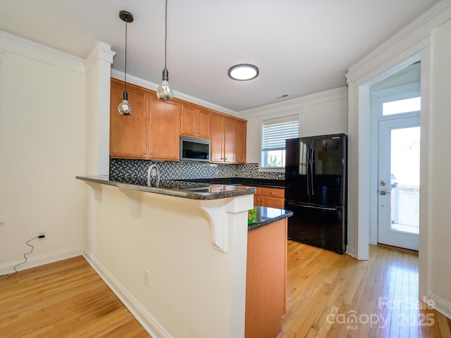 kitchen featuring freestanding refrigerator, a peninsula, light wood-type flooring, and stainless steel microwave