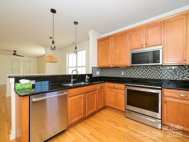 kitchen with light wood finished floors, a sink, a peninsula, decorative backsplash, and stainless steel appliances
