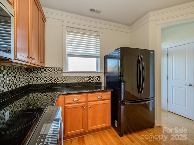 kitchen with freestanding refrigerator, brown cabinetry, light wood-type flooring, and visible vents
