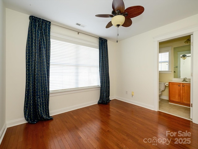 spare room featuring wood-type flooring, visible vents, baseboards, and ceiling fan
