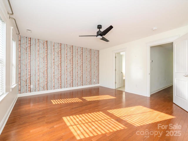 spare room with visible vents, wood finished floors, baseboards, and ceiling fan