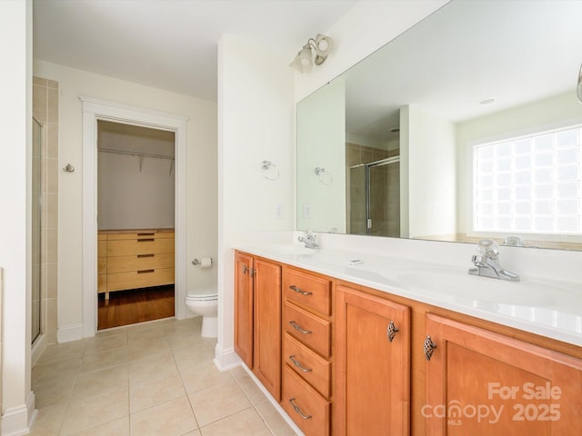 bathroom with a stall shower, double vanity, a sink, and tile patterned floors