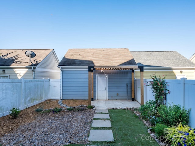 back of property with a shingled roof and a fenced backyard