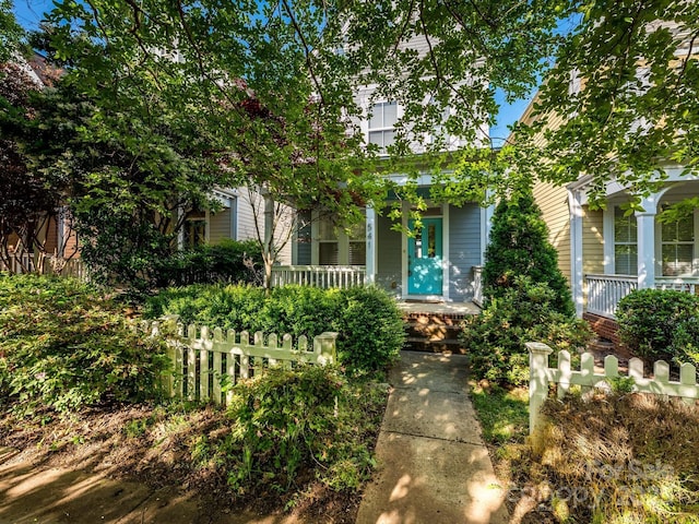 obstructed view of property with covered porch and fence